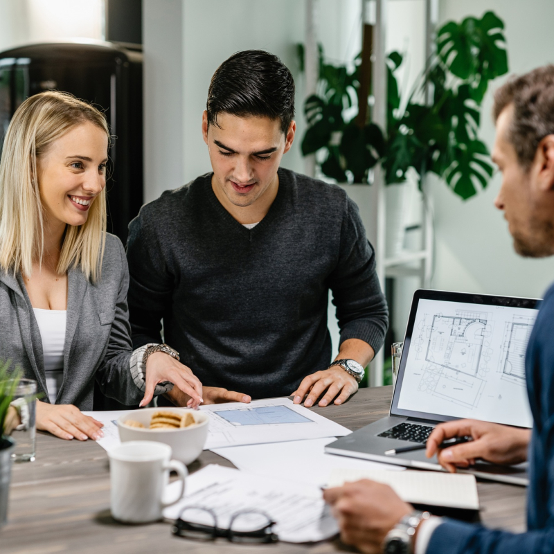 Happy couple consulting with real estate agent about housing plans on a meeting.